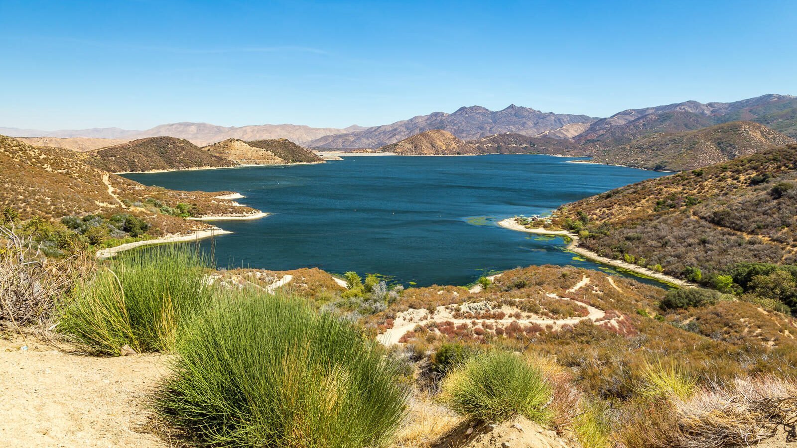 Silverwood Lake, a serene mountain oasis enveloped by lush grass, offers a picturesque retreat.